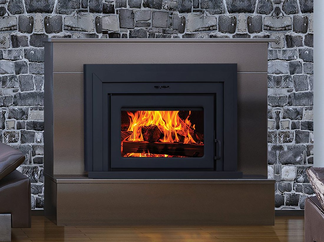 Le foyer encastrable Fusion vu de près : la porte d’acier noir et la vitre remplie de flammes, dans le manteau de pierre